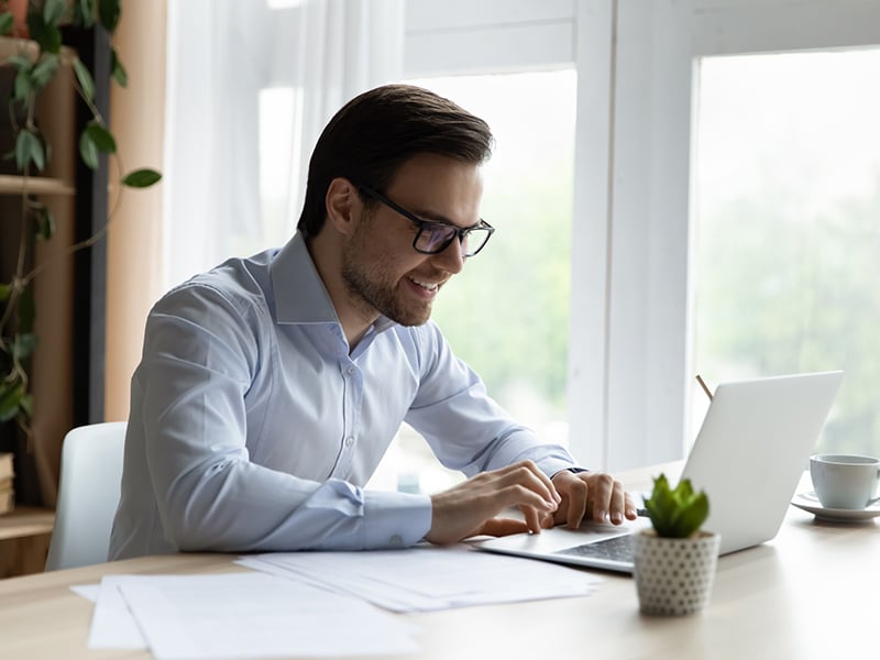 Happy millennial business leader working on a laptop from home