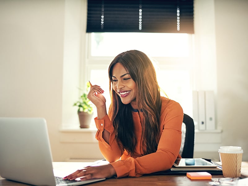 Smiling-young-female-entrepreneur-working-on-a-laptop-at-home