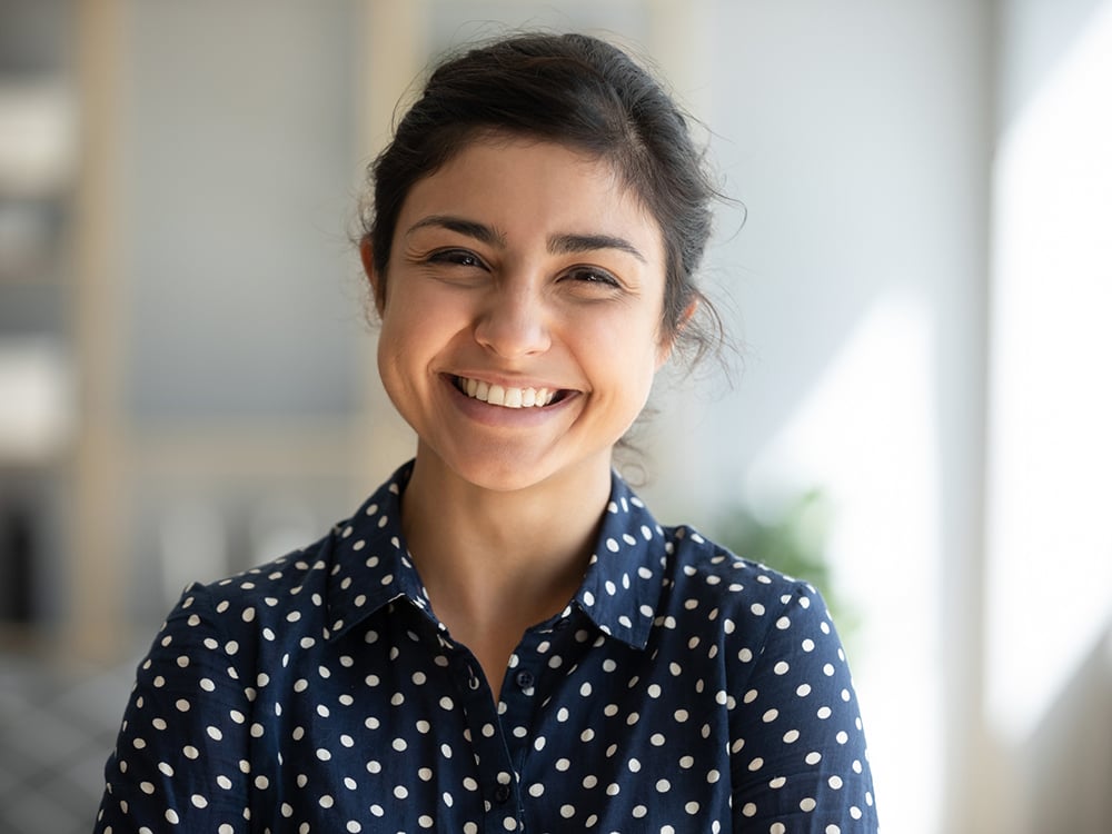 Smiling woman in a dark blue shirt with white polka dots