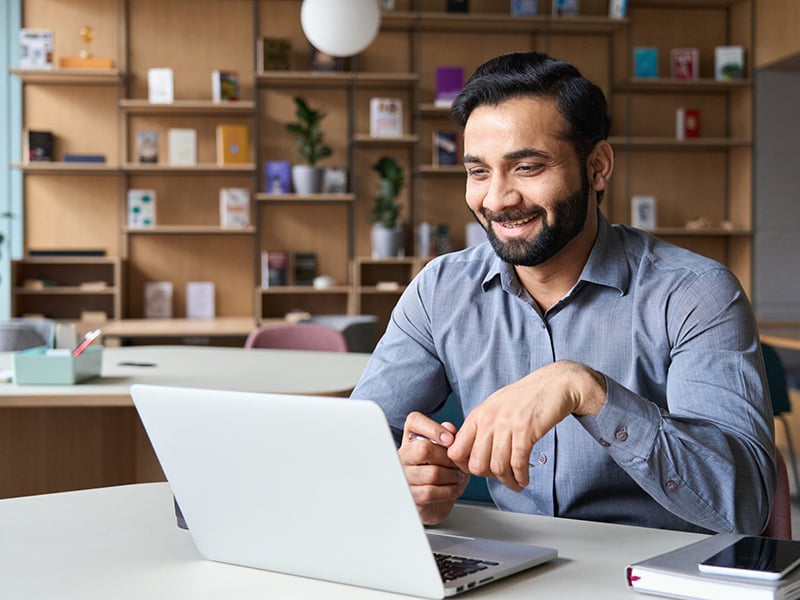 Smiling businessman sitting in front of a laptop