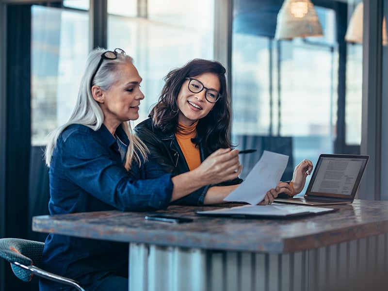 Two-women-analyzing-documents-at-office