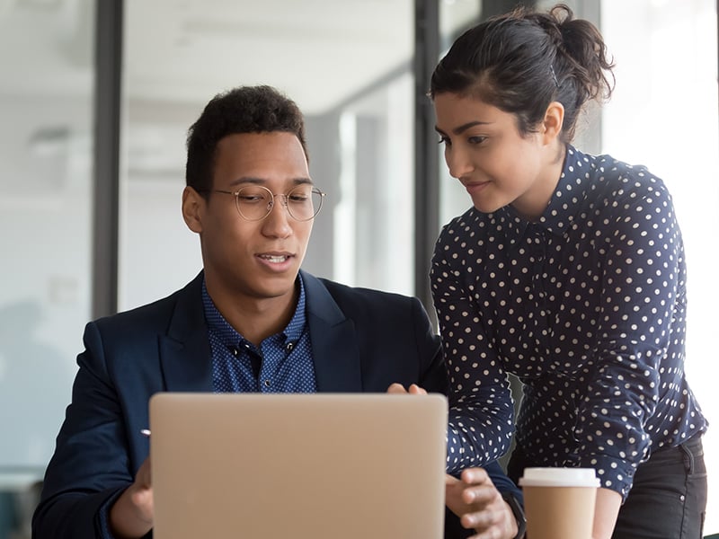 Male and female coworker view information on a laptop